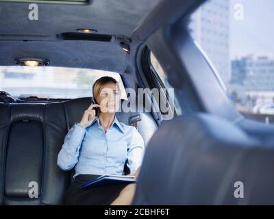 Geschäftsfrau Im Gespräch Auf Handy Reisen In Limousine Stockfoto