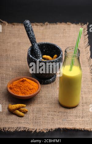 Kurkuma-Getränk, Latte, Tee, Milch mit Zimt in einem Glaskrug mit frischem und getrocknetem Kurkuma. Stockfoto