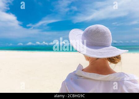 Frau am Strand entspannen, Sommerurlaub Konzept, glückliche Frau mit weißem Kleid, Hut entspannen in der Hängematte am tropischen Strand bei Sonnenuntergang Stockfoto