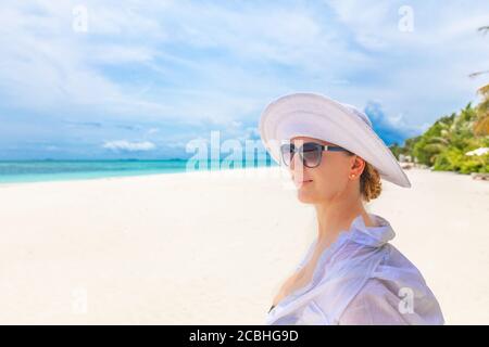 Frau am Strand entspannen, Sommerurlaub Konzept, glückliche Frau mit weißem Kleid, Hut entspannen in der Hängematte am tropischen Strand bei Sonnenuntergang Stockfoto