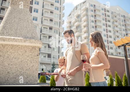 Schönes Paar grillen Fleisch im Hof und Wein trinken Stockfoto