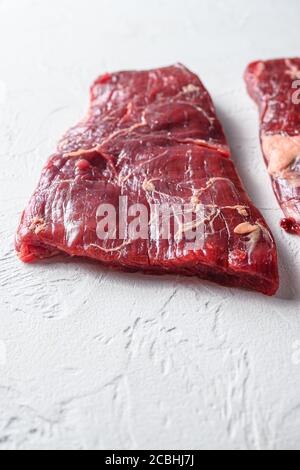 RAW Flap Meat, London Broil Bio Fleisch geschnitten Seitenansicht Nahaufnahme über weißem Beton Hintergrund vertikalen selektiven Fokus Stockfoto