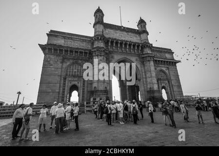 Mumbai, Indien - 22. November 2019: Berühmtes Tor zu Indien in Mumbai, Indien. Schwarzweiß-Fotografie. Massen von Touristen im Vordergrund. Stockfoto