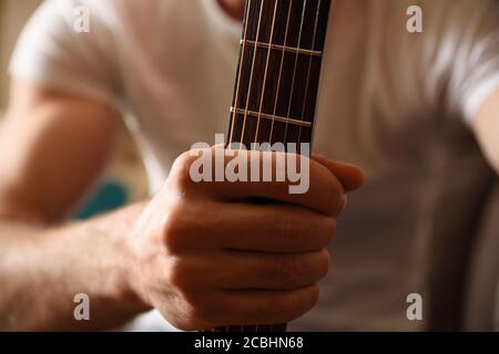 Nahaufnahme des Mannes in weißem Kurzarm-T-Shirt Aufnahme akustische Gitarre am Hals Stockfoto