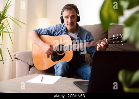 Home Recording-Ausrüstung für Musik mit Akustikgitarre, Mikrofon und Laptop auf Holztisch. Draufsicht Stockfoto