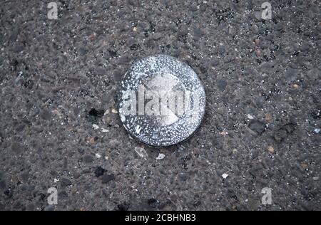 Berlin, Deutschland. August 2020. Auf einem Parkplatz eines Supermarkts in der Tiroler Straße in Pankow liegt ein verbranntes BMW-Emblem eines bei einem Brand heruntergefallenen Fahrzeugs. In der Nacht vom Freitag brannten vier Autos auf dem Parkplatz. Nach Angaben der Feuerwehr wurde niemand verletzt. Die Feuerwehr teilte mit, dass das Feuer Brandstiftung gewesen sein könnte. Details waren zunächst nicht verfügbar. Quelle: Paul Zinken/dpa-Zentralbild/dpa/Alamy Live News Stockfoto