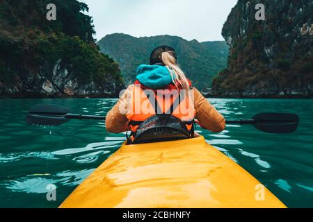 Frau paddelt Kajak im See mit türkisfarbenem Wasser. Getöntes Foto. Winter. Stockfoto