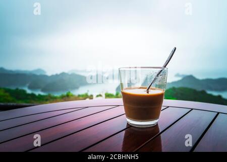 Heißer Milchkaffee im Vietnam-Stil. Frühstück mit einem wunderschönen Blick auf die Felsen, die aus dem Wasser ins Meer ragen. Ha Long Bay im Norden Stockfoto