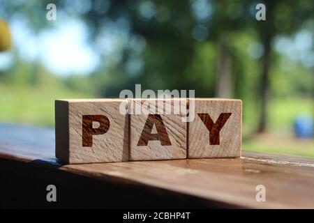 Bezahlen Sie auf Holzwürfel mit Natur Hintergrund. Gebühren und Steuern Finanzkonzept Stockfoto