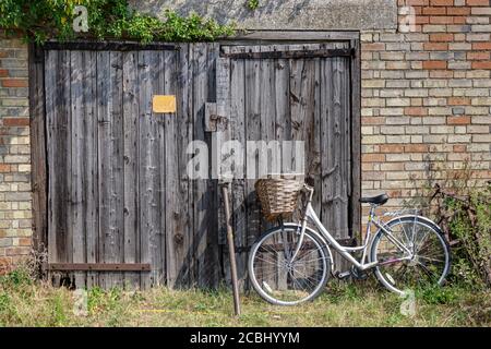 Traditionelle Damen Fahrrad mit Korbkorb gegen Scheune Tür gestützt Stockfoto