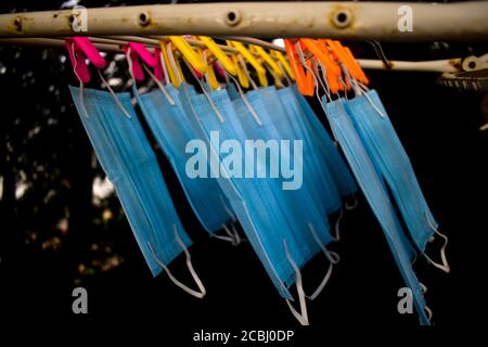 Ein Bündel von blauen Gesichtsmasken werden an einem Tuch Stange zum Trocknen Zweck nach der Reinigung sie für die Wiederverwendung aufgehängt. Wiederverwendbare Masken mit aufgehängten Clips Stockfoto