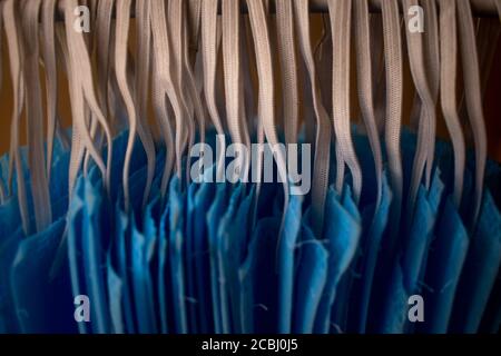 Ein Bündel von blauen Gesichtsmasken werden an einem Tuch Stange zum Trocknen Zweck nach der Reinigung sie für die Wiederverwendung aufgehängt. Wiederverwendbare Masken mit aufgehängten Clips Stockfoto