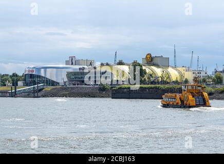 Hamburg, Deutschland - 8. Juni 2020: Das Entertainment Theater auf der anderen Seite der Landungsbrücken. Eine Fähre überquert die elbe. Stockfoto