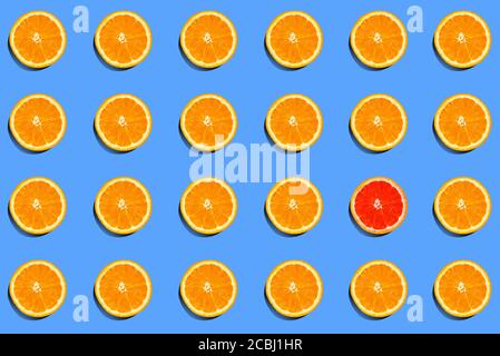 Muster aus frischen orangefarbenen Scheiben und einem roten auf blauem Hintergrund. Individualität und Differenzkonzept. Heraussticht. Draufsicht. Flache Lay-Komposition Stockfoto