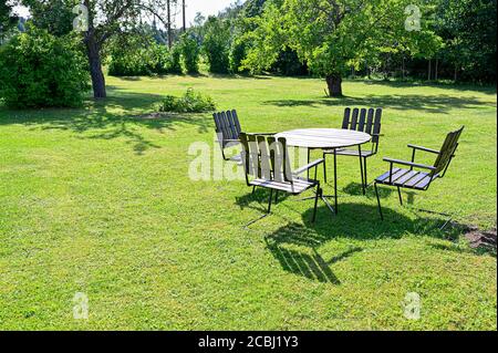 Gartentisch aus Holz und vier Stühle auf einer grünen Wiese Stockfoto