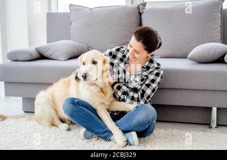 Glückliche Frau streicheln niedlichen Hund in Licht Wohnung Stockfoto