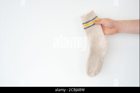 Beige Wollsocke in der Hand auf hellem Hintergrund Stockfoto