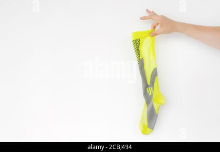 Stinkende gelbe Laufsocke in der Hand auf hellem Hintergrund Stockfoto