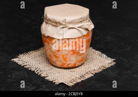 Hausgemachtes Sauerkraut mit Karotte im Glas auf schwarzem Hintergrund. Fermentierte Nahrung, natürliches Probiotikum. Rustikaler Stil. Hausgemachte Gurkenscheiben. Gesunde Ernährung Stockfoto