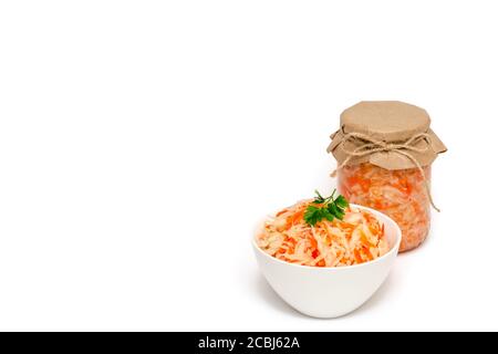 Hausgemachtes Sauerkraut mit Karotte in weißer Keramikschale und einem Glas auf weißem Hintergrund. Fermentierte Lebensmittel. Gesunde Ernährung und Diät-Konzept. Nahaufnahme Stockfoto