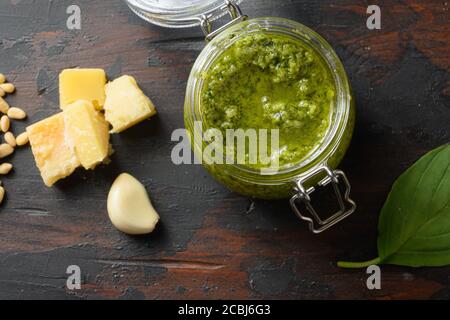 Pesto alla Genovese in Glas mit Zutaten Parmesan Basilikum Pinienkernen. Auf dunklen Holz Tischplatten vintage Seitenansicht Stockfoto