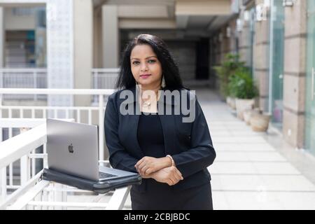 Eine Inderin arbeitet auf ihrem Laptop in einer städtischen Unternehmensumgebung, Stockfoto