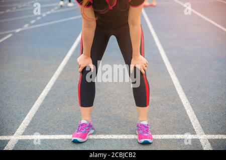 Laufsportlerin Knieverletzung und Schmerzen. Frau leidet unter schmerzhaften Knie beim Laufen auf der blau gummierten Laufstrecke. Stockfoto