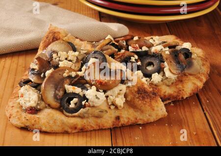 Naan Brot belegt mit schwarzen Oliven, sautierten Champignons, Fetakäse und hummus Stockfoto