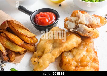 Fishand Chips zerschlagen knusprig Kabeljau Filet Detail mit Dip und Zitrone in einem Papierkegel auf weißem Hintergrund mit allen Komponenten klassische Rezept zum Mitnehmen Stockfoto