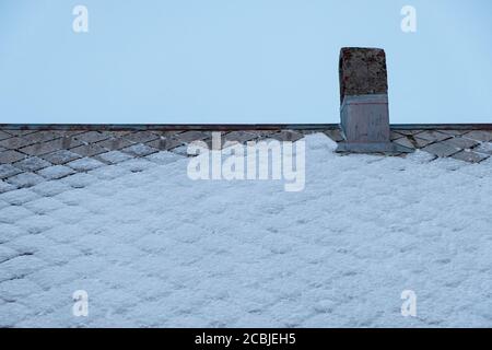 Kamin des Kamins auf dem Dachhaus mit Schnee bedeckt Bedeckt Stockfoto