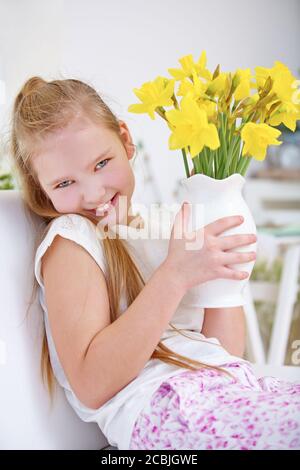 Happy Child hält eine Vase mit viel Gelb Narzissen Stockfoto