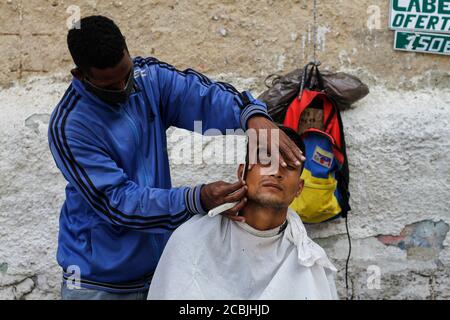 Caracas, Venezuela. August 2020. Ein Friseur schneidet die Haare eines Kunden auf der Straße. Insgesamt sind fast 30,000 Menschen in Venezuela mit dem Coronavirus infiziert worden und mehr als 245 starben im Zusammenhang mit Covid-19. Die Pandemie verschärft die soziale Krise im südamerikanischen Land. Kredit: Pedro Rances Mattey/dpa/Alamy Live Nachrichten Stockfoto