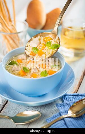 Hühnersuppe mit Gemüse in einer blauen Schüssel auf dem Esstisch, Draufsicht. Stockfoto