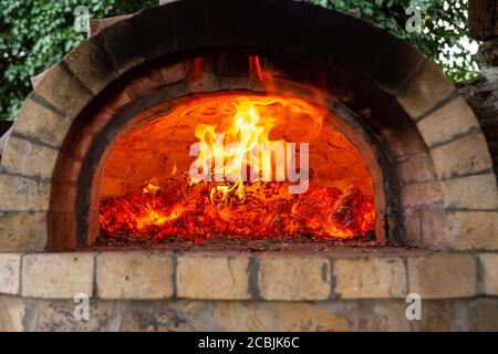 Brennendes Eichenholz in einem Ofen. Herd im Landhaus. Helle Flamme über heißen Kohlen. Stockfoto