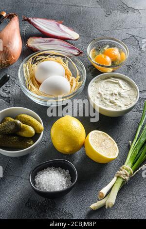 Ranch-Sauce in einer weißen Porzellanschale mit Zutaten Eier Kapern, Gemüse, Kräuter und Gewürze auf einem grauen Stein texturierte Tabelle Seitenansicht Stockfoto