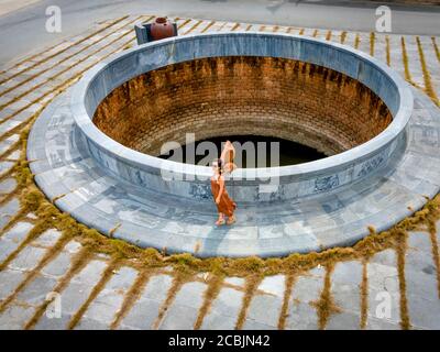 Nghe an Provinz, Vietnam - 31. Juli 2020: Eine Touristenfrau steht an einem alten Brunnen in der Provinz Nghe an, Vietnam Stockfoto