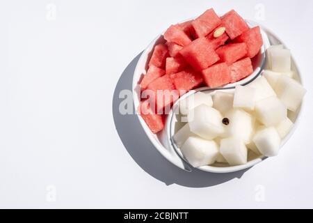 Reife Wassermelone und Melone, in Würfel geschnitten, auf einer Yin-Yang-Schale ausgelegt. Saftige, reife Sommerfrüchte. Helles Licht. Leerzeichen für Text. Stockfoto