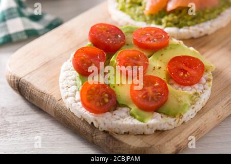 Reiskuchen mit Tomaten und Avocado auf Holztisch Stockfoto