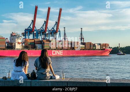 Containerschiff ONE am Burchardkai, Container Terminal, Junge Frauen an der Kaimauer in Övelgönne Nähe Elbstrand, Hamburger Hafen, Hafenkraene, Deutsc Stockfoto