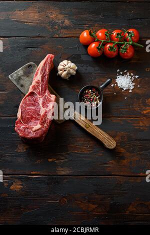 Roh Beef Rib Steak auf Fleischspalter. Bio-Bauernhof marmorierte Prime schwarz angus Rindfleisch. Dunkler Holzhintergrund. Draufsicht. Mit Gewürzen, Pfefferkörnern Stockfoto