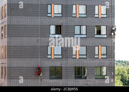 Moskau, Russland - 6. Juni 2019: Zwei professionelle Industriekletterer in Helm und Uniform bei der Arbeit, Waschen Gebäudefassade. Stockfoto