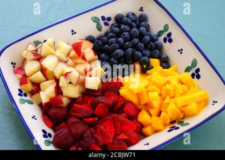 Ein gesunder Obstteller mit frischer Mango, Pfirsichen und Beeren Stockfoto
