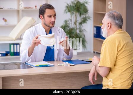Alter Hals verletzten Mann besucht jungen Arzt Stockfoto