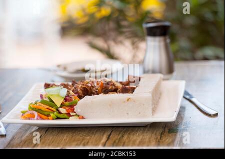 Nsima oder Ugali oder Posho ist eine Hauptmahlzeit für Millionen von Menschen in Afrika südlich der Sahara. Im Volksmund gegessen mit Nyama choma, Ziegenfleisch oder einfach nur Gemüse Stockfoto