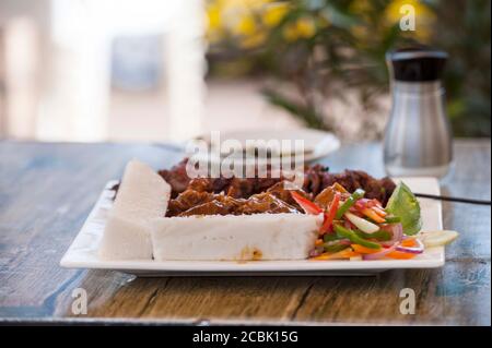 Nsima oder Ugali oder Posho ist eine Hauptmahlzeit für Millionen von Menschen in Afrika südlich der Sahara. Im Volksmund gegessen mit Nyama choma, Ziegenfleisch oder einfach nur Gemüse Stockfoto