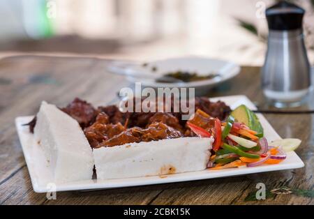 Nsima oder Ugali oder Posho ist eine Hauptmahlzeit für Millionen von Menschen in Afrika südlich der Sahara. Im Volksmund gegessen mit Nyama choma, Ziegenfleisch oder einfach nur Gemüse Stockfoto