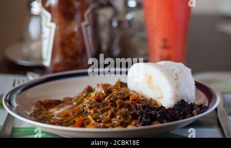 Nsima, auch als Ugali oder Posho bekannt, ist eine Hauptmahlzeit für Millionen in Afrika. Eine beliebte Kombination mit Nyama Choma Stockfoto