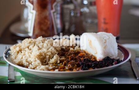 Nsima, auch als Ugali oder Posho bekannt, ist eine Hauptmahlzeit für Millionen in Afrika. Eine beliebte Kombination mit Nyama Choma und Reis Stockfoto