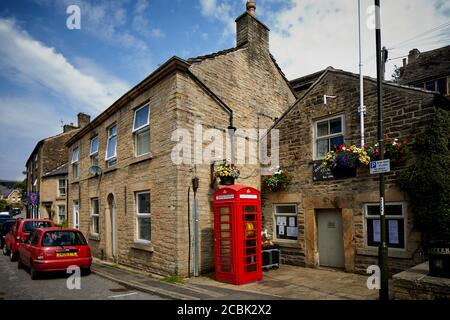 Hayfield Village, High Peak, Derbyshire, gemeinderatsgebäude mit Defibrillator in einer alten roten Telefonbox auf der Market Street Stockfoto