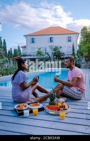 Französisches Ferienhaus mit Holzterrasse und Swimmingpool in der Ardeche Frankreich. Pärchen entspannen sich am Pool mit Holzterrasse während eines Luxusurlaubs Stockfoto